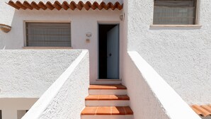 A white building with a blue door and terracotta steps leading to a window. - Casa Dell Asfodelo by Wonderful Italy (Budoni)
