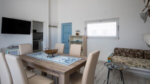 A dining area with a wooden table, beige chairs, and a blue patterned table runner. - Casa Dell Asfodelo by Wonderful Italy (Budoni)