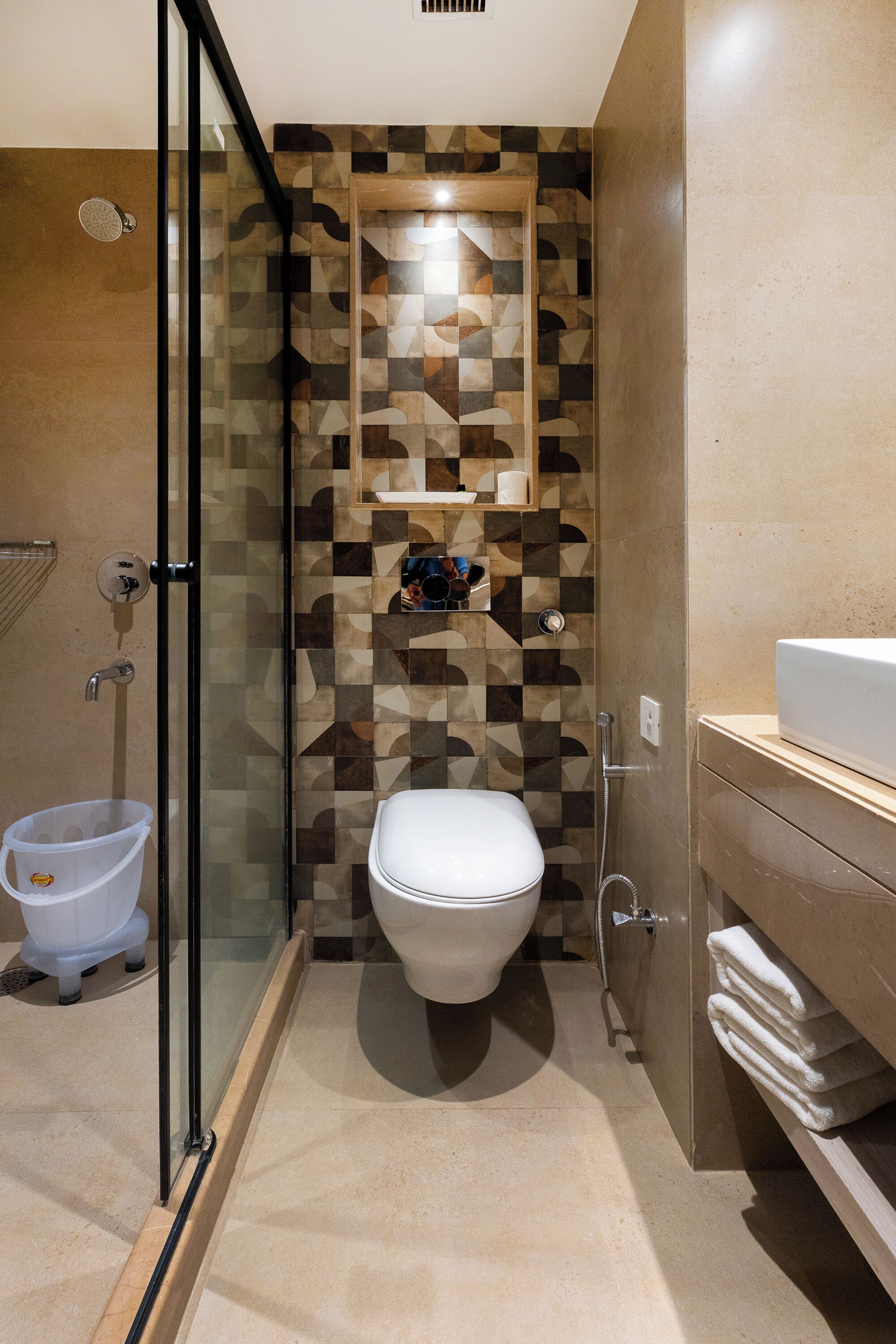 A modern bathroom with a glass-enclosed shower, a toilet, and a sink with a towel rack.