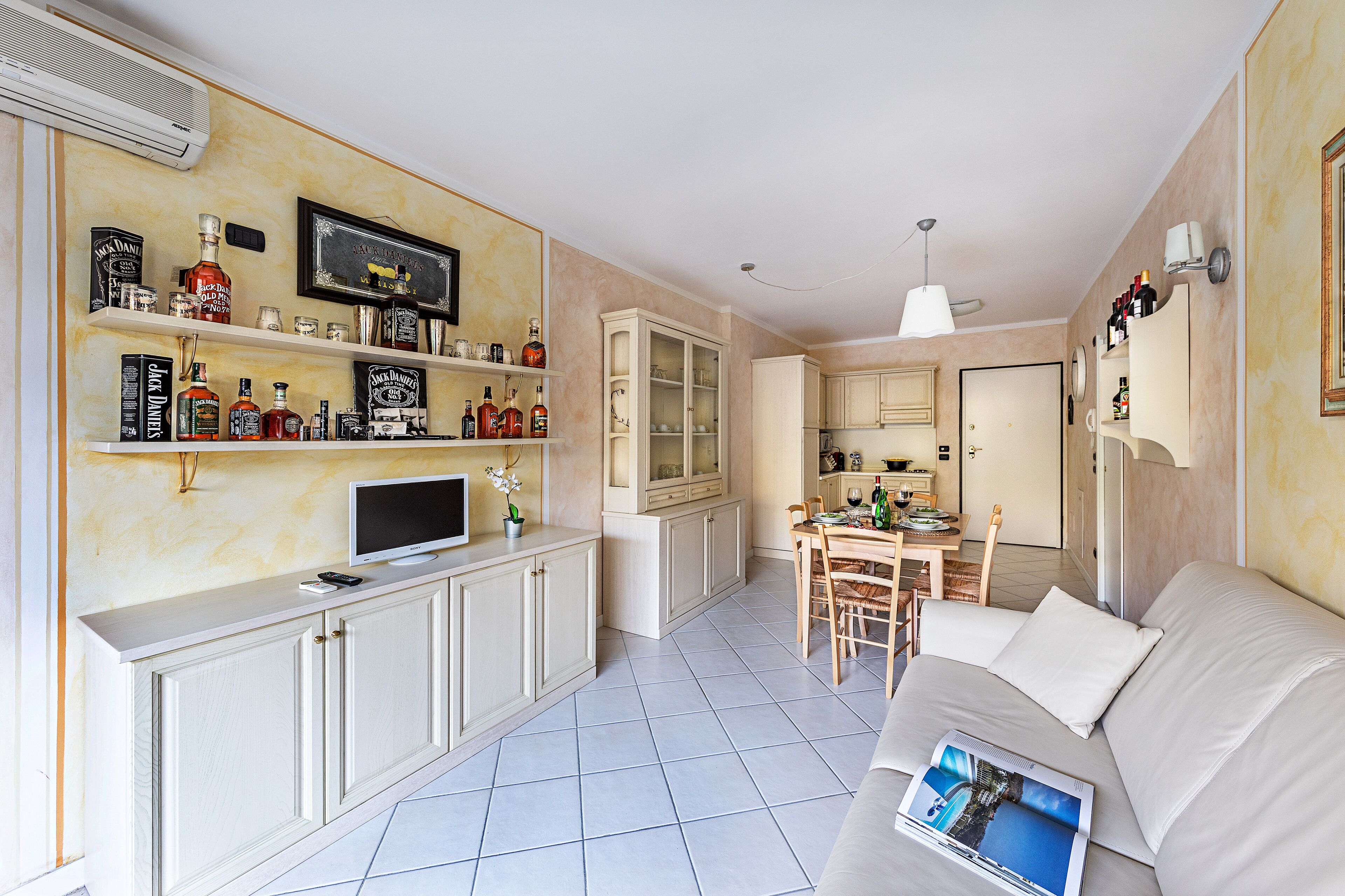 Un salon moderne avec un canapé, un coin repas comprenant une table et des chaises, et une cuisine équipée de meubles et d’un téléviseur.