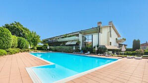A modern pool area with a rectangular pool, sun loungers, and a building with large windows and a flat roof. - Residence Villa Giulia 5-03 with pool by Wonderful Italy (Desenzano del Garda)