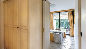 A bedroom with a large wardrobe, a bed, and a view of a garden through a sliding door. - Residence Villa Giulia 5-03 with pool by Wonderful Italy (Desenzano del Garda)