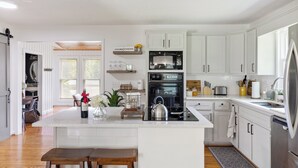 Une cuisine moderne avec des meubles blancs, un îlot central et un réfrigérateur en acier inoxydable.