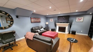 A modern living room with a fireplace, leather sofas, a coffee table, and a TV mounted above the fireplace.