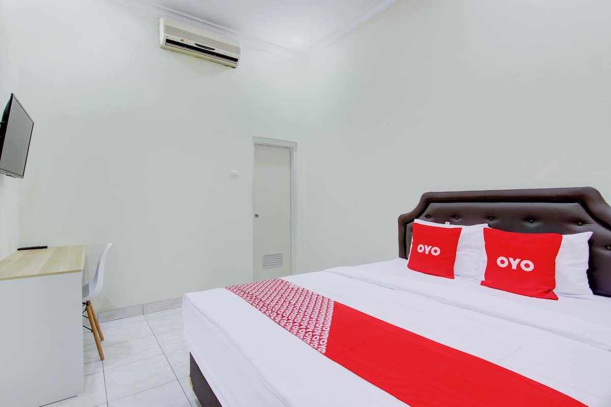 A hotel room with a bed, a desk, and a chair.