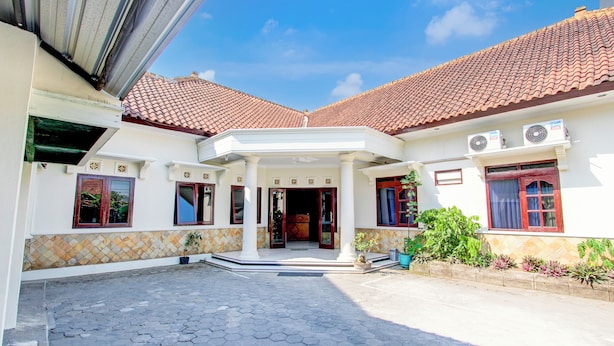 A two-story house with a tiled roof, a central entrance with a covered porch, and a paved courtyard. - Hotel O Syariah Griya Wisata (Wonogiri)