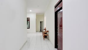 A hallway with a wooden chair and a dark wooden door. - Hotel O Syariah Griya Wisata (Wonogiri)