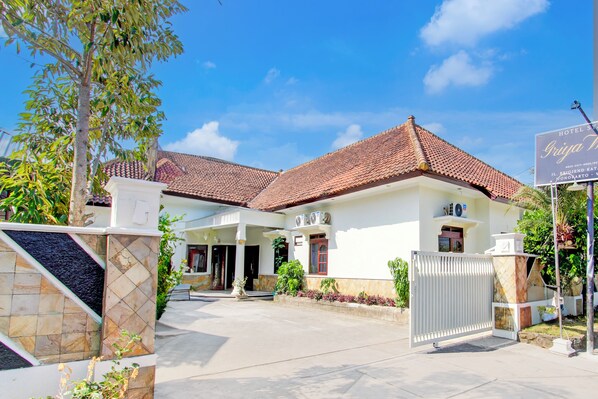 A hotel with a tiled roof, a gated entrance, and a signboard.