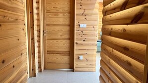 Een gang met houten lambrisering aan beide kanten en een deur aan het einde.