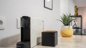 Eine moderne Küche mit Kaffeemaschine, Mülleimer und Topfpflanze.