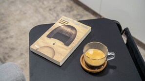 A book titled "Valter Hugo Maia" and a glass of coffee on a table. - OASIS @Avenida da República (Vila Nova de Gaia)