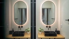 A mirrored bathroom vanity with a black sink, two potted plants, and a modern light fixture. - OASIS @Avenida da República (Vila Nova de Gaia)