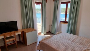 A bedroom with a bed, a desk, a television, and a window with curtains. - Villa Riva (Omisalj)