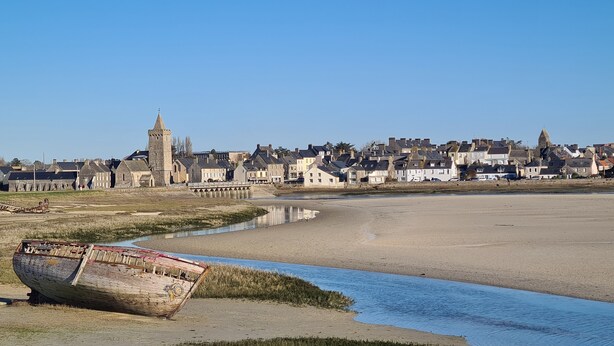 A riverside town with historic buildings, a prominent tower, and a boat on the shore. - Maison Dans Lotissement Très Calme 300 Mètres du Centre Ville .10 km de la mer (La Haye)