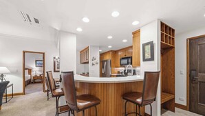 A modern kitchen with a central island, wooden cabinets, and a microwave. - The Charter at Beaver Creek A260 (Beaver Creek)