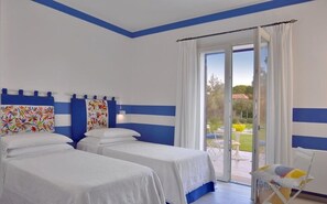 A hotel room with two beds, a balcony with a view of the garden, and a chair. - Villa in Marina Di Bibbona with 4 bedrooms sleeps 8 (Marina Di Bibbona)