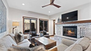 Un salon moderne doté d’une cheminée, de sièges confortables et d’un ventilateur de plafond.