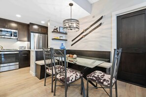 Una cocina moderna con armarios de madera oscura, electrodomésticos de acero inoxidable y una mesa de comedor de vidrio con sillas de metal.