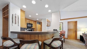 Una cocina compacta con armarios de madera, una isla central con taburetes altos y un microondas.