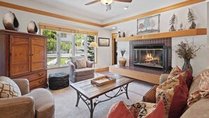 A cozy living room with a fireplace, wooden furniture, and a ceiling fan. - The Charter at Beaver Creek A3505 (Beaver Creek)