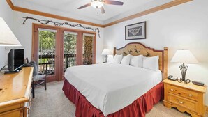 A bedroom with a large bed, wooden headboard, bedside tables, a ceiling fan, and a balcony with glass doors. - The Charter at Beaver Creek A3505 (Beaver Creek)