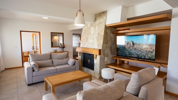 A modern living room with a stone fireplace, a flat-screen TV, a sofa, and a coffee table.