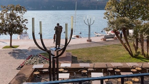 En terrass vid sjön med utomhusmöbler, en menorah och en staty.