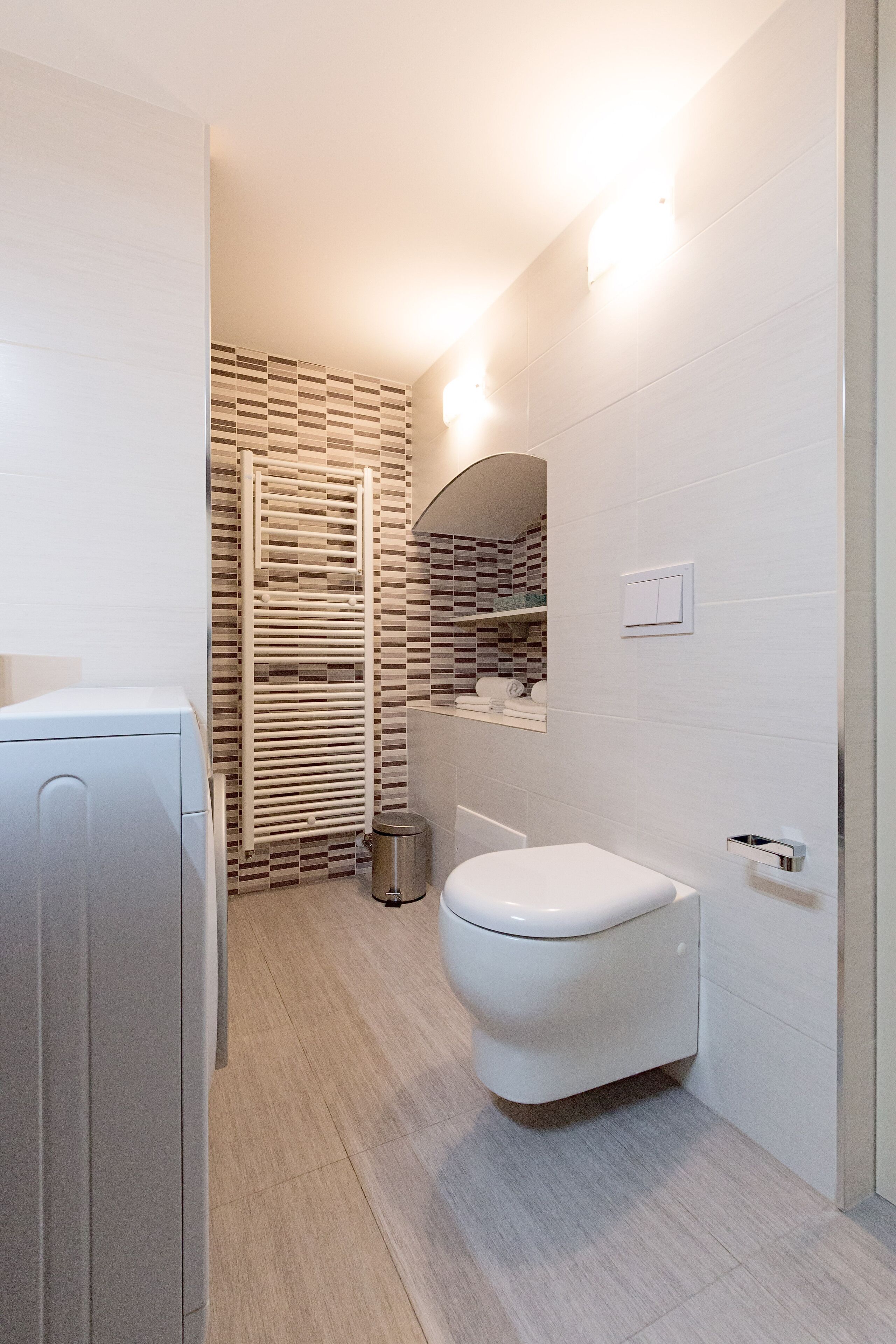 Un baño moderno con inodoro blanco, toallero y espejo.