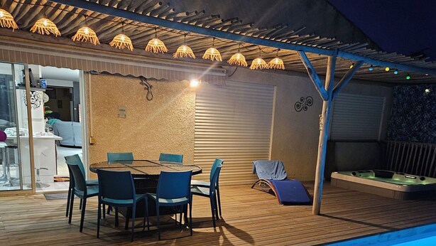 Un área de piscina al aire libre con terraza de madera, un espacio de estar techado con sillas y un jacuzzi.