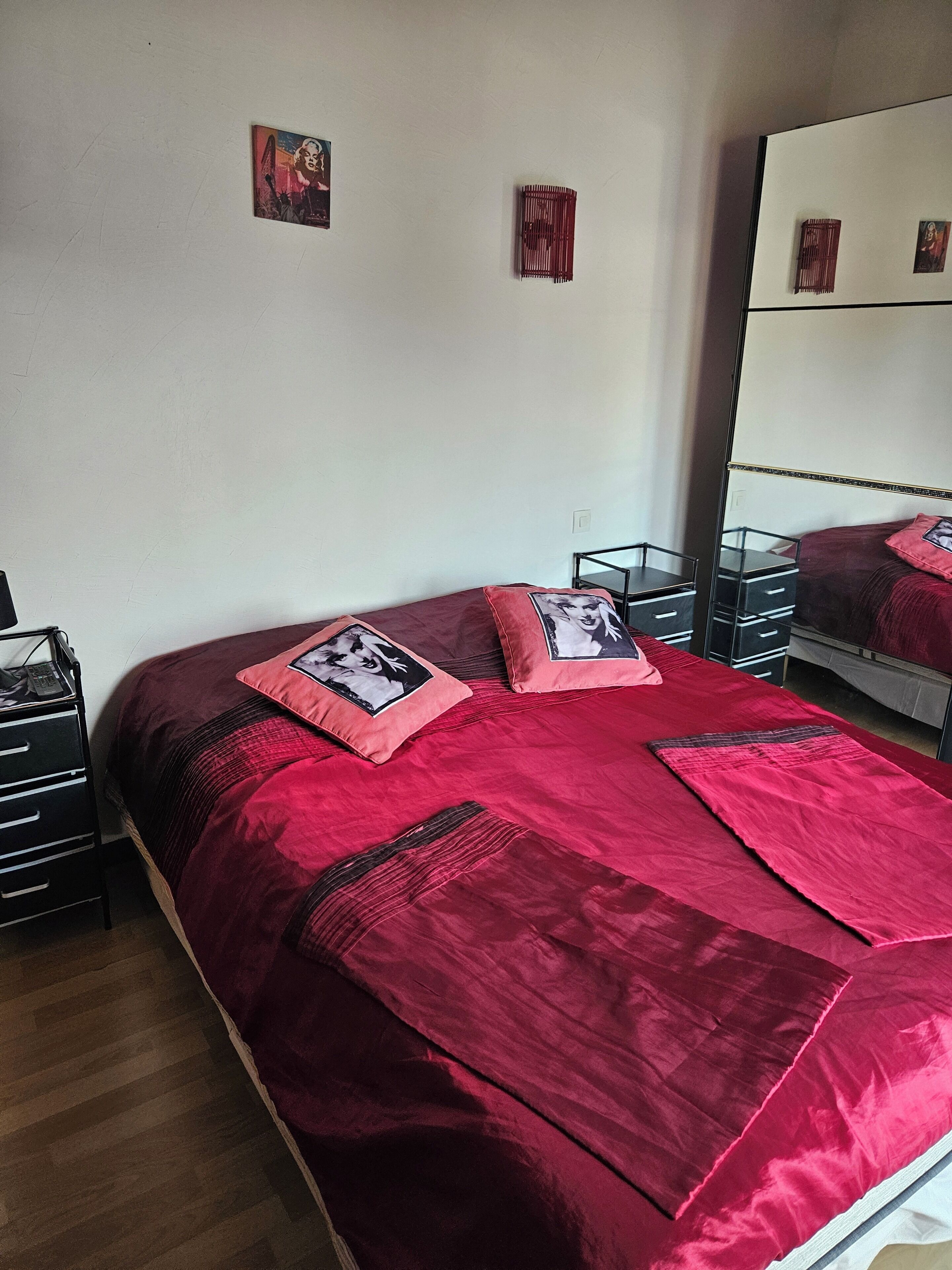 Ein Schlafzimmer mit einem großen Bett, einem Schminktisch, einem Spiegel und zwei an der Wand befestigten Bildern.