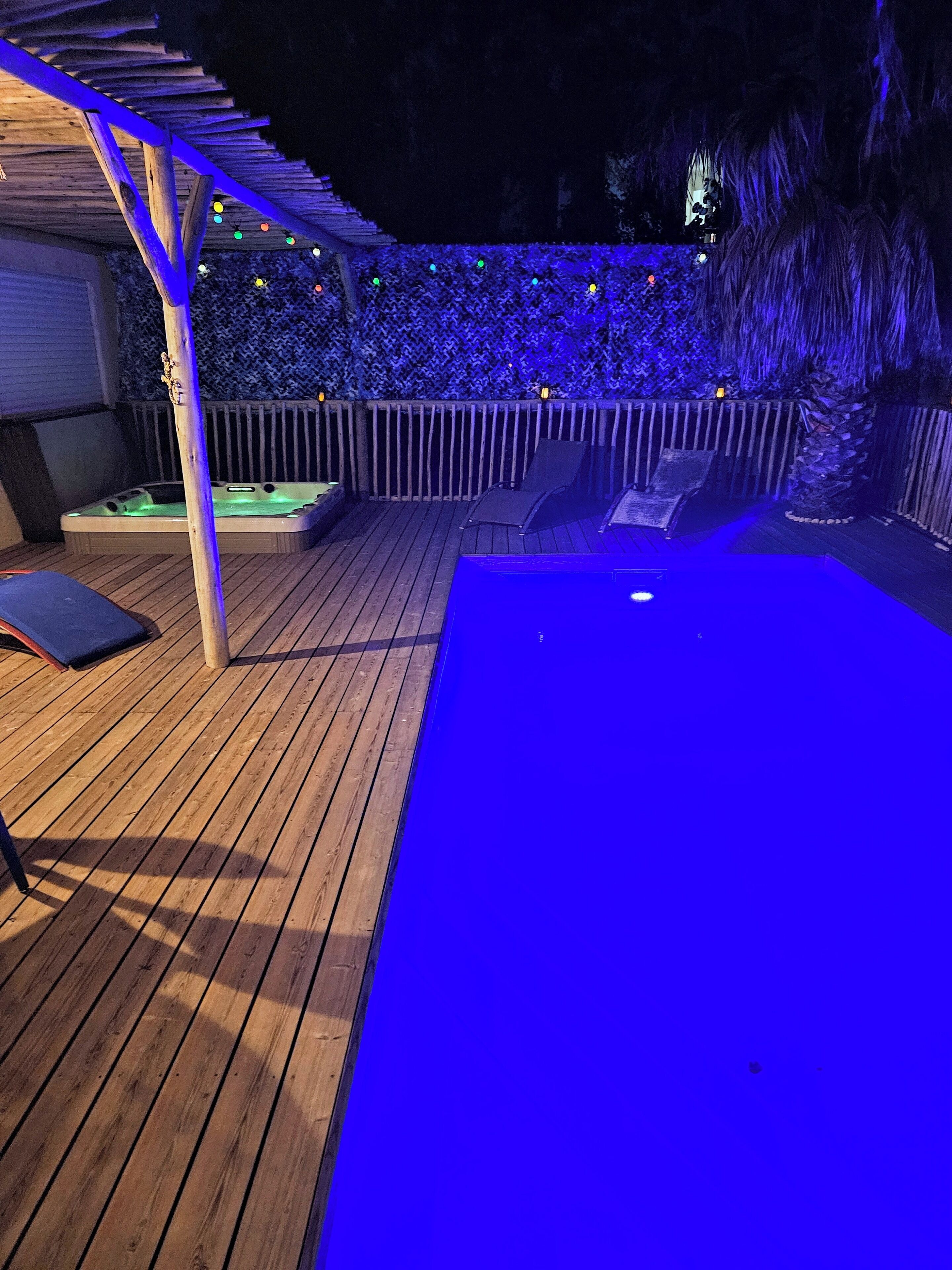 Una terraza de madera con un jacuzzi, sillones de descanso y una pérgola.