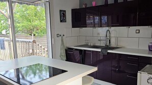 Cocina moderna con una isla central, armarios oscuros y un amplio ventanal con vistas a zonas verdes.