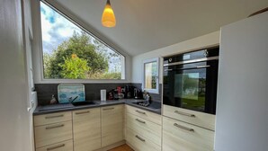 Een moderne keuken met een groot raam, een inbouwoven en een spoelbak.