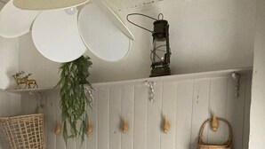Een keuken met witte houten kastjes, een hanglamp, een mand en een plant.