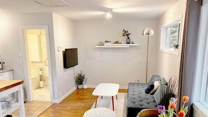 Una sala de estar moderna con un televisor de pantalla plana, un sofá gris, una mesa blanca y piso de madera.