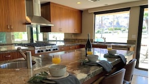 Una cocina moderna con una isla grande, electrodomésticos de acero inoxidable y vistas al exterior.