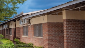 A row of brick houses with attached air conditioning units, a clear sky, and a well-maintained garden. - Liwonde Park Motel (Liwonde)