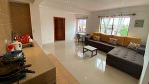 A modern living room with a sofa, a dining table, and a kitchen area with a stove. - Black Pearl (Puerto Villamil)