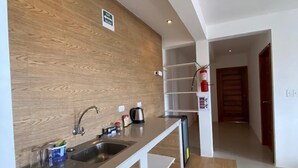 A modern kitchen with a wooden backsplash, stainless steel sink, and a built-in dishwasher. - Black Pearl (Puerto Villamil)