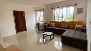 A spacious living room with a large sofa, a coffee table, and a dining area with a chair and table. - Black Pearl (Puerto Villamil)