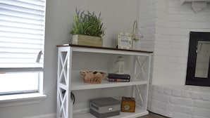 Ein weißes Holzregal mit einer Pflanze, einem Laternen und Büchern.