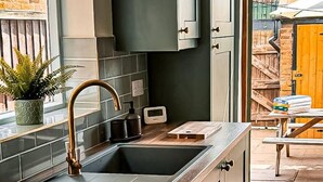 Una cocina moderna con armarios oscuros, un grifo de cobre y una pequeña encimera.