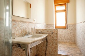 A bathroom with a sink, mirror, and window. - Ortigia Seafront Apartment by Wonderful Italy (Syracuse)