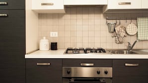 A kitchen with dark wooden cabinets, a white countertop, a gas stove, and a stainless steel sink. - Via de' Falegnami 6 Apartment by Wonderful Italy (Bologna)