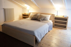 Une chambre à coucher avec un lit, une tête de lit en bois, des tables de chevet et un radiateur.
