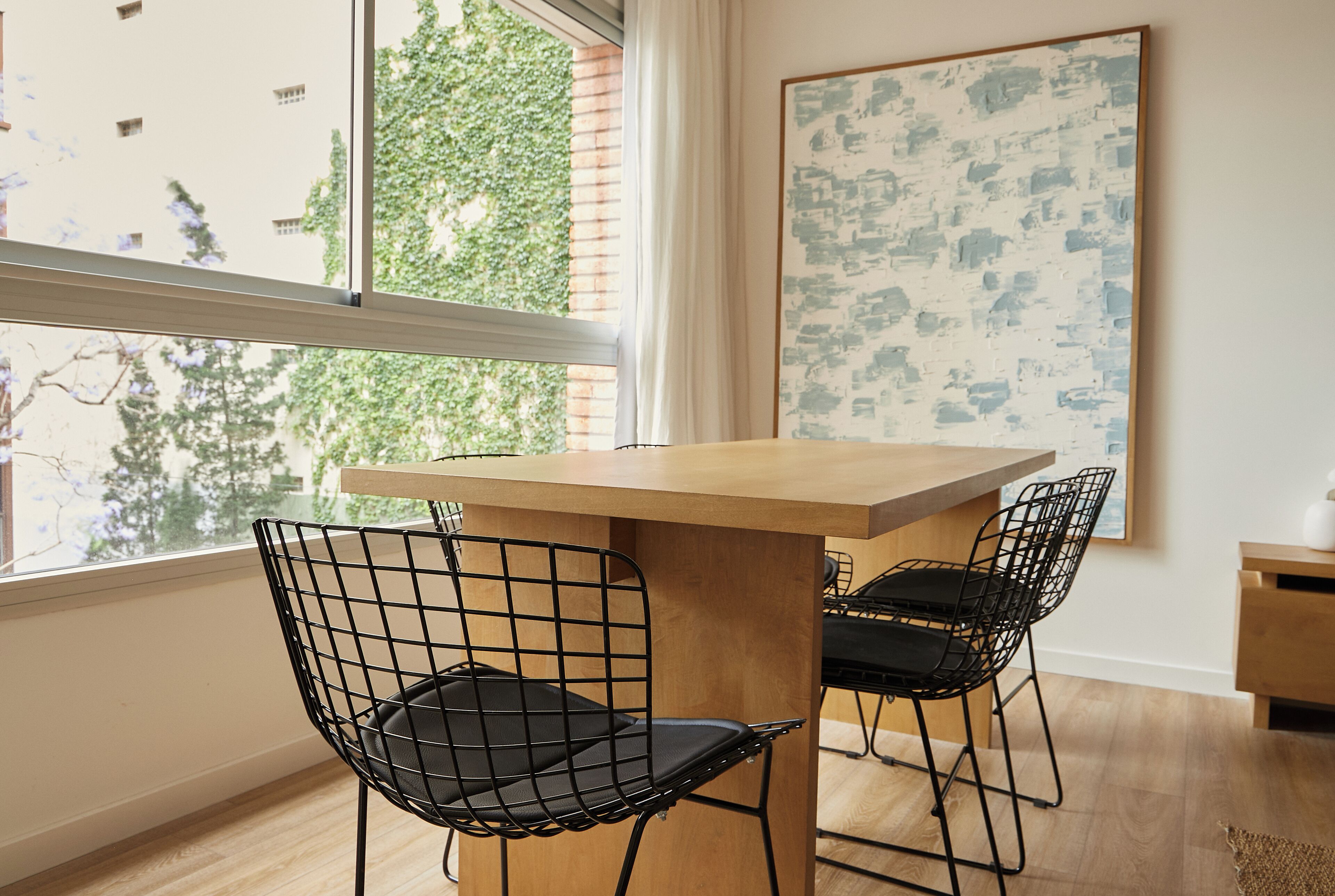 Un comedor con una mesa de madera y dos sillas de estructura metálica negra.