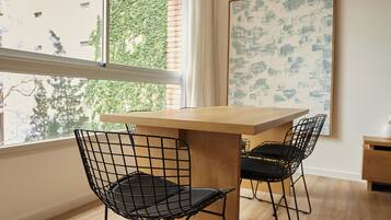 Un comedor con una mesa de madera y dos sillas de estructura metálica negra.