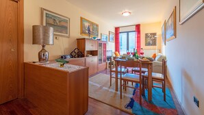 Un rincón comedor acogedor con una mesa y sillas de madera, una lámpara y vista a la cocina al fondo.