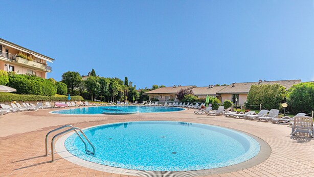 Zona de piscina con sillas de descanso y una escalera para la piscina.