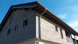 Un edifici amb teulada inclinada, diverses finestres i una gutxera visible.